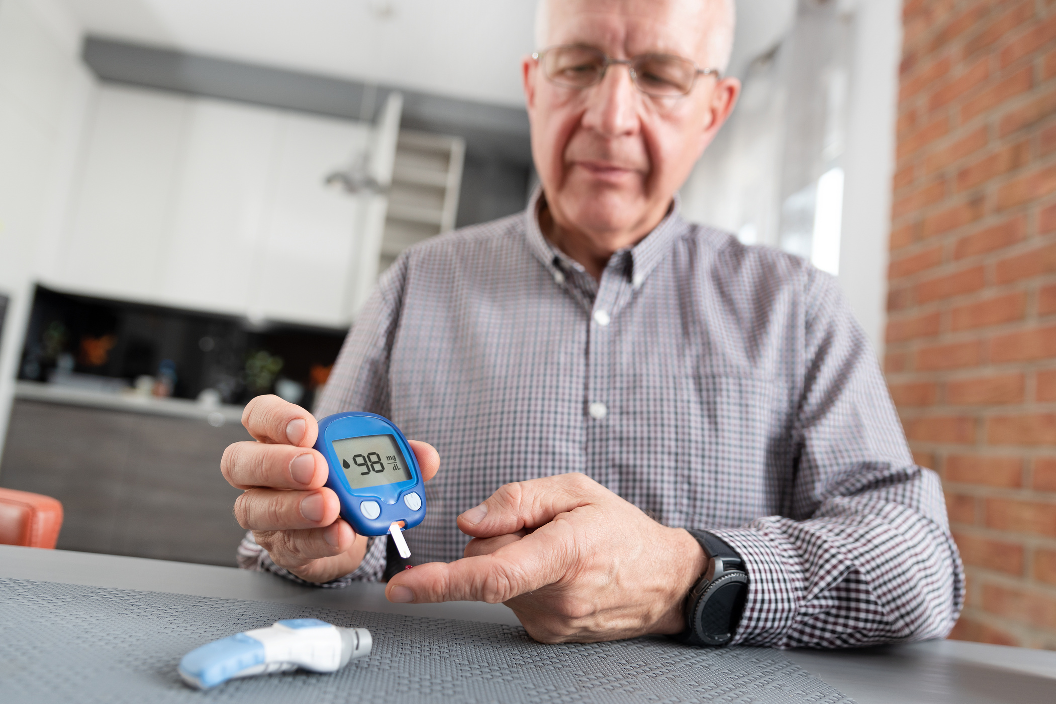 a man tests his blood sugar level by testing blood from his finger
