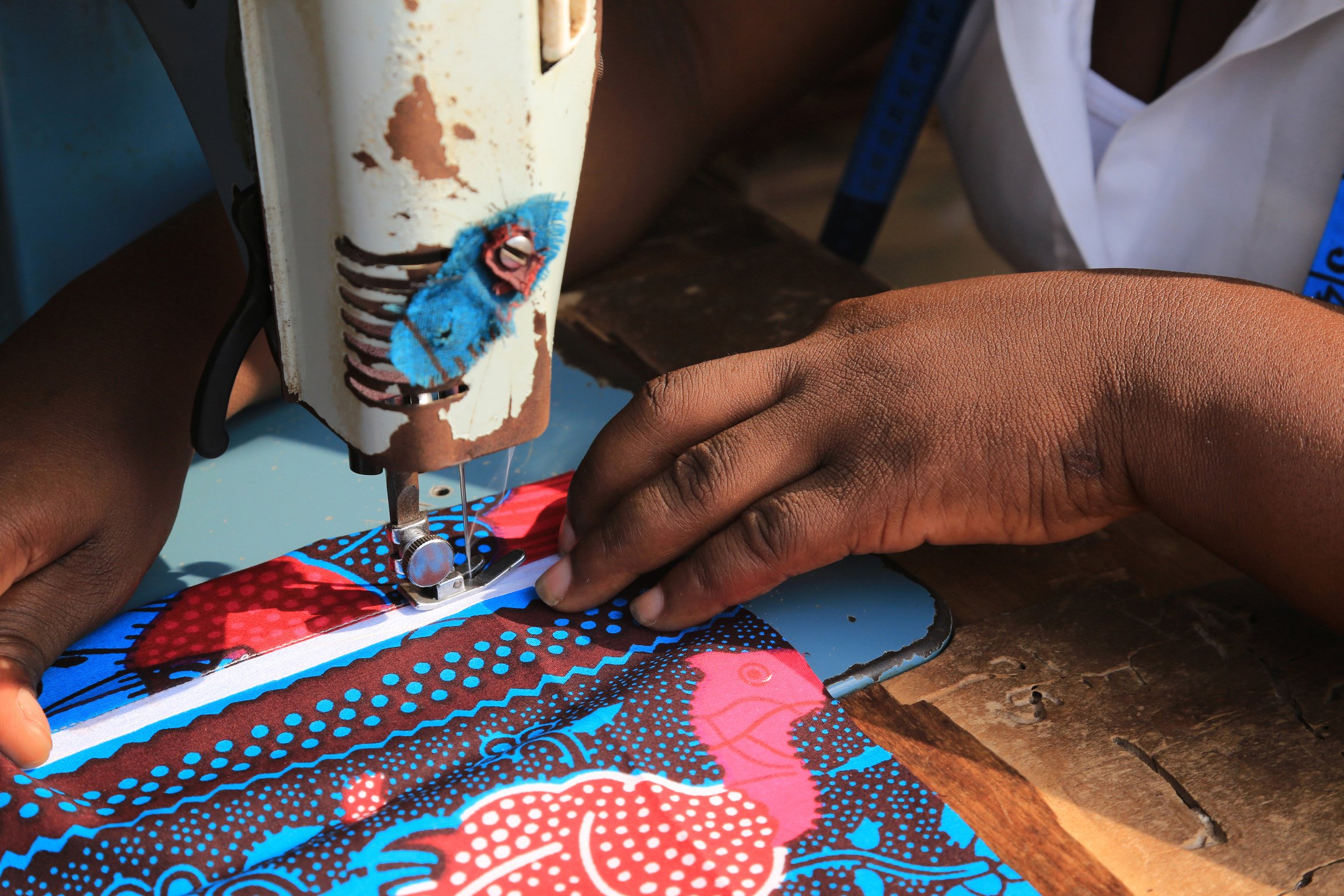 A person using a sewing machine to make a piece of fabric.