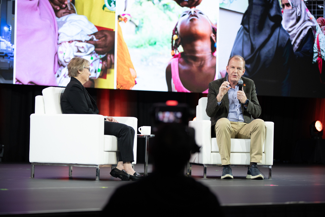 two people sitting on chairs in front of a large screen