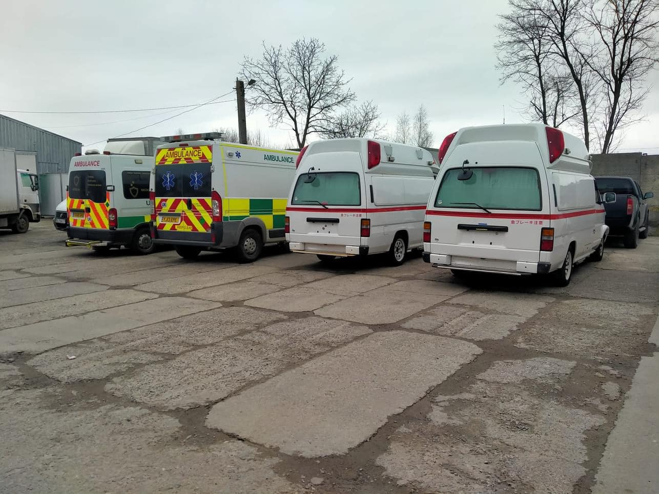 Two ambulances and two 4x4's parked next to each other in a car park.