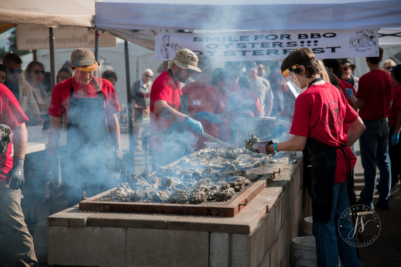 a group of people in red shirts cooking on an outdoor grill