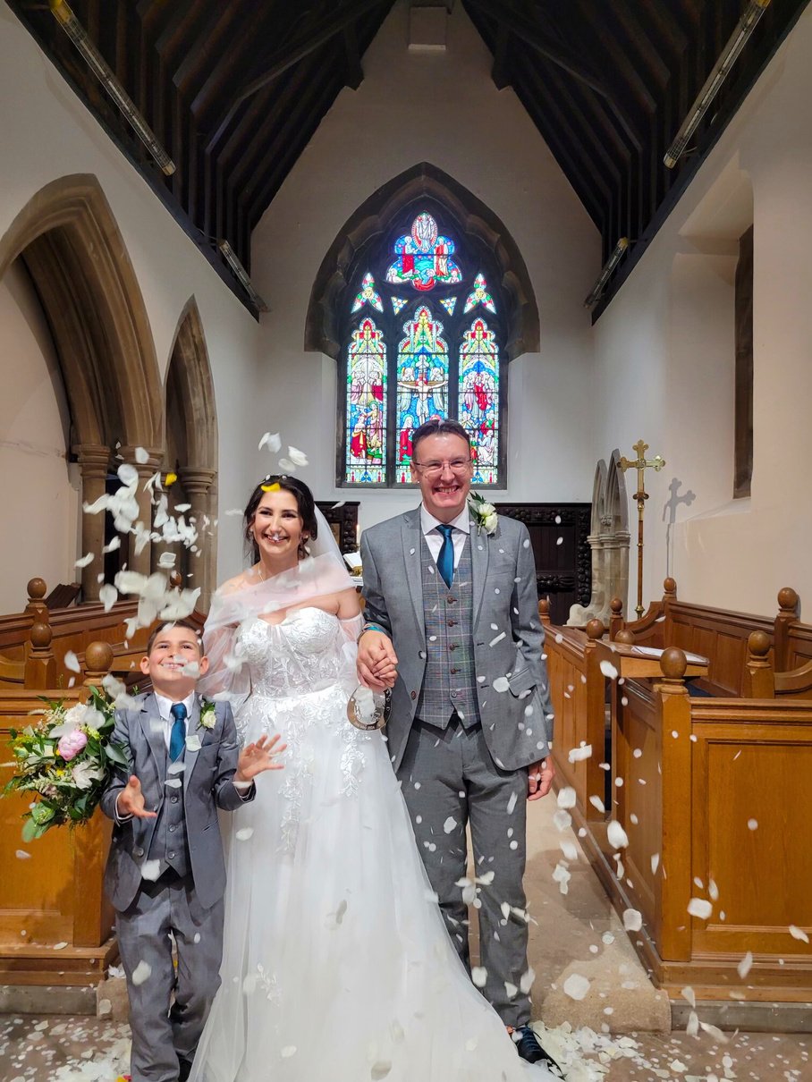 A bride and groom are surrounded by confetti in a church