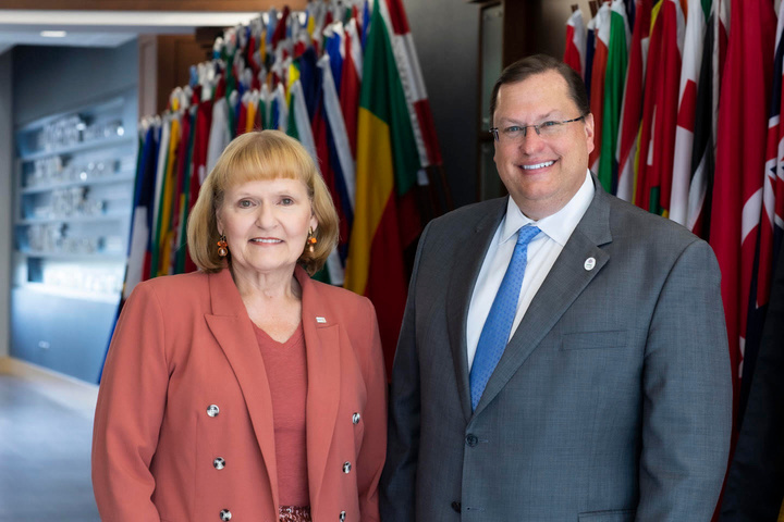 Two people standing next to each other in front of flags