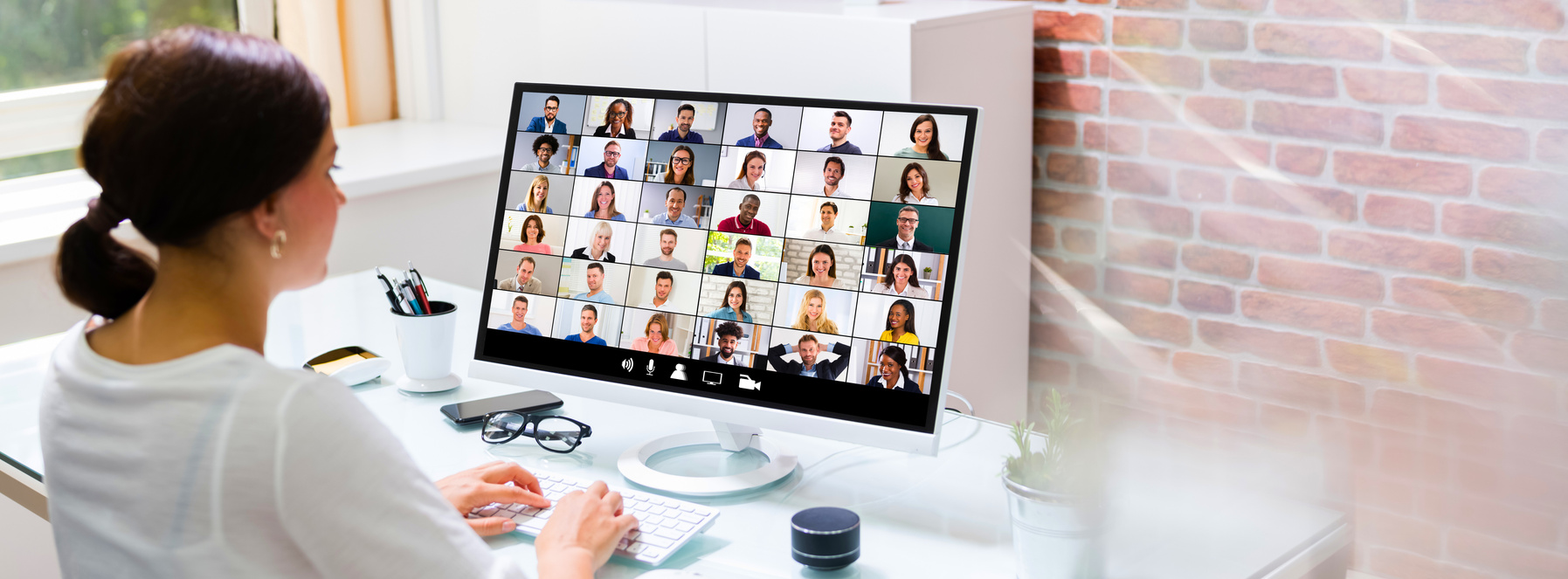 a person sitting at a desk in front of a computer screen with many people on it