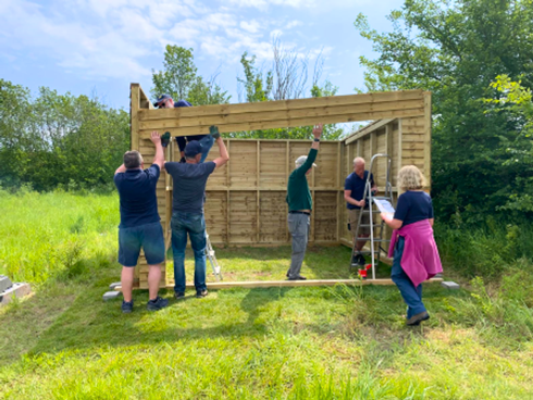 a group of people working on a shed in the woods