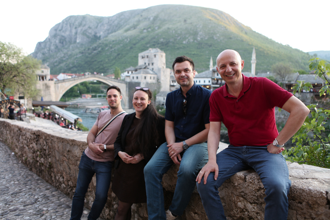 a group of people sitting on a stone wall in front of a river