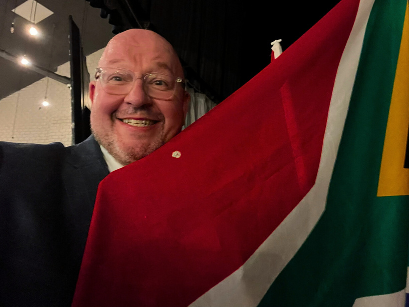 man stands in front of south africa flag