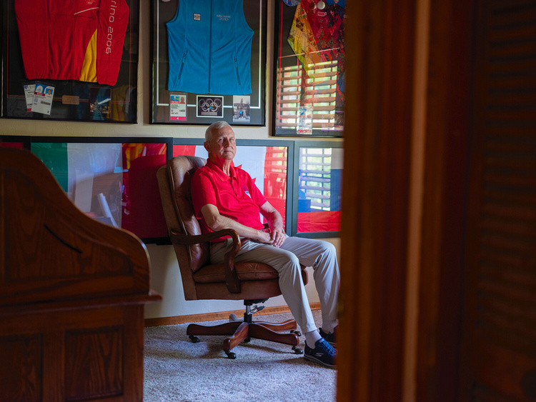 a man sat in his office chair surrounded by olympic flags and tracksuits