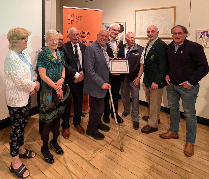 a group of people standing together in a room holding an award