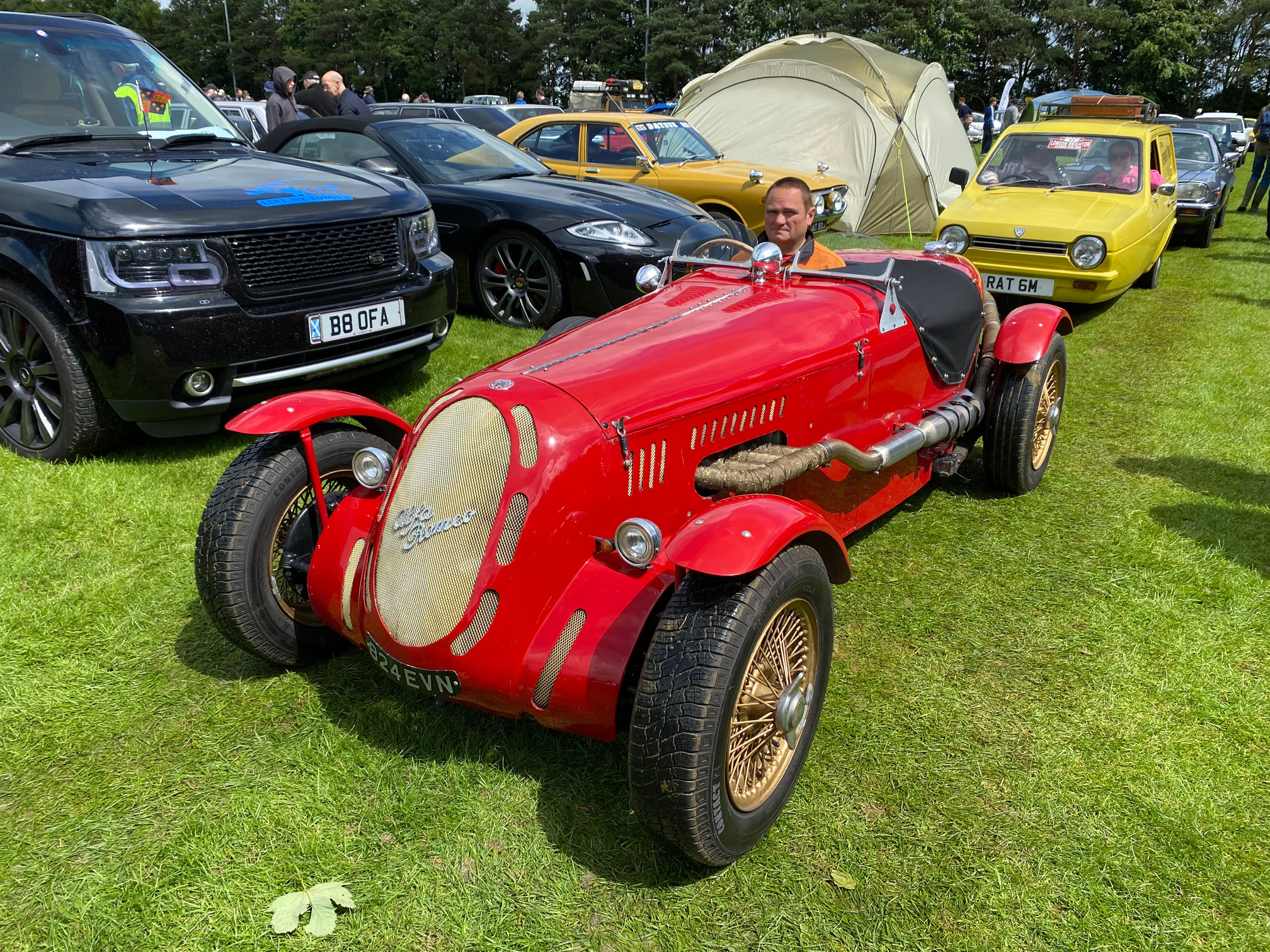 A vintage red race car is on display at a car show