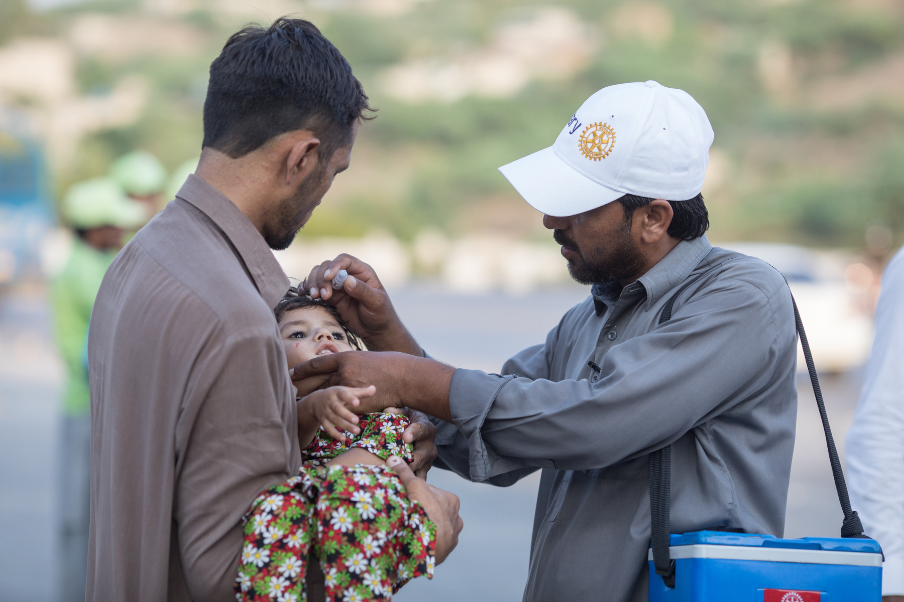 vaccinator squeezes drops from a polio vaccine into a young child's mouth