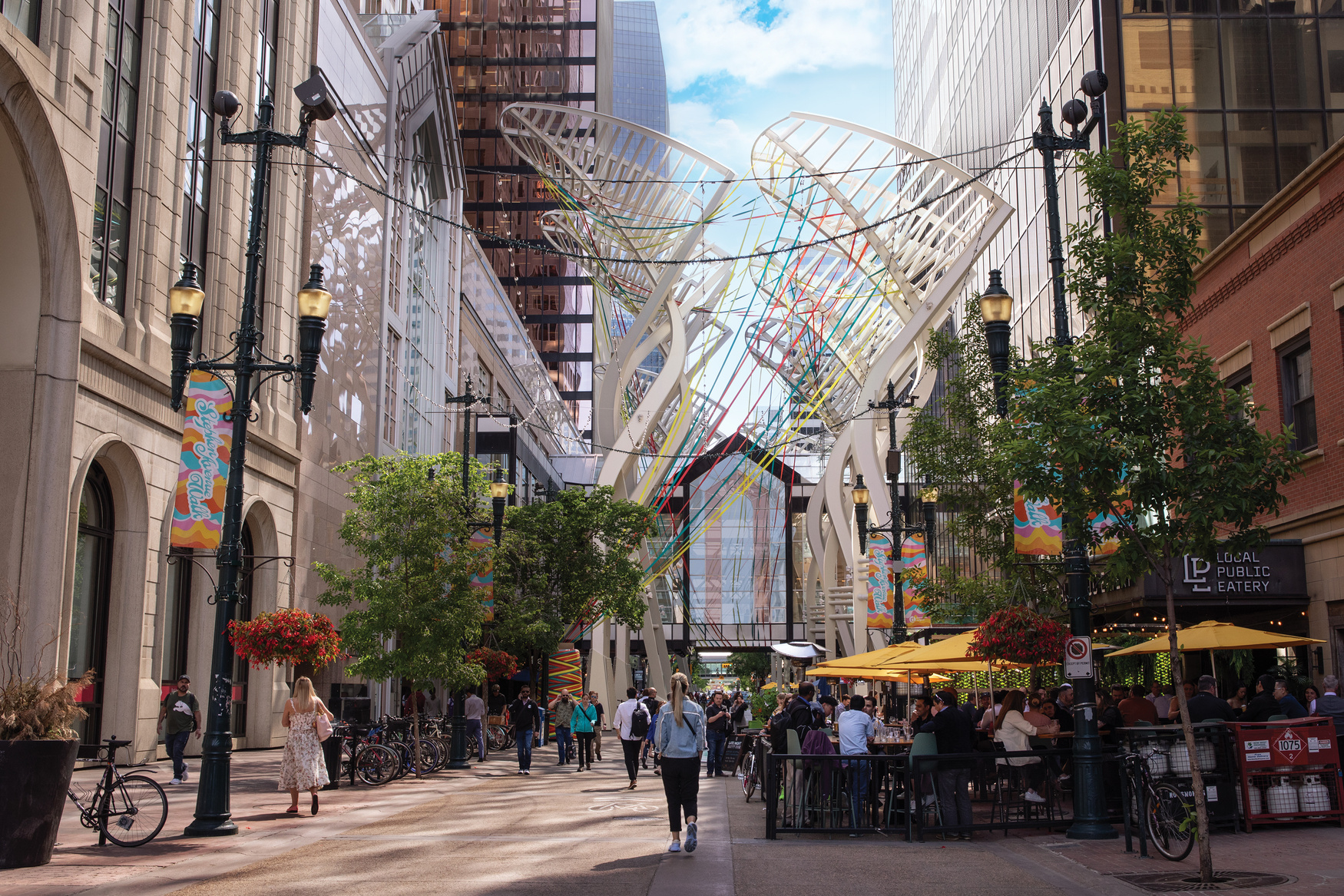 a city street in Calgary with people walking and sitting at tables at outdoor restaurants