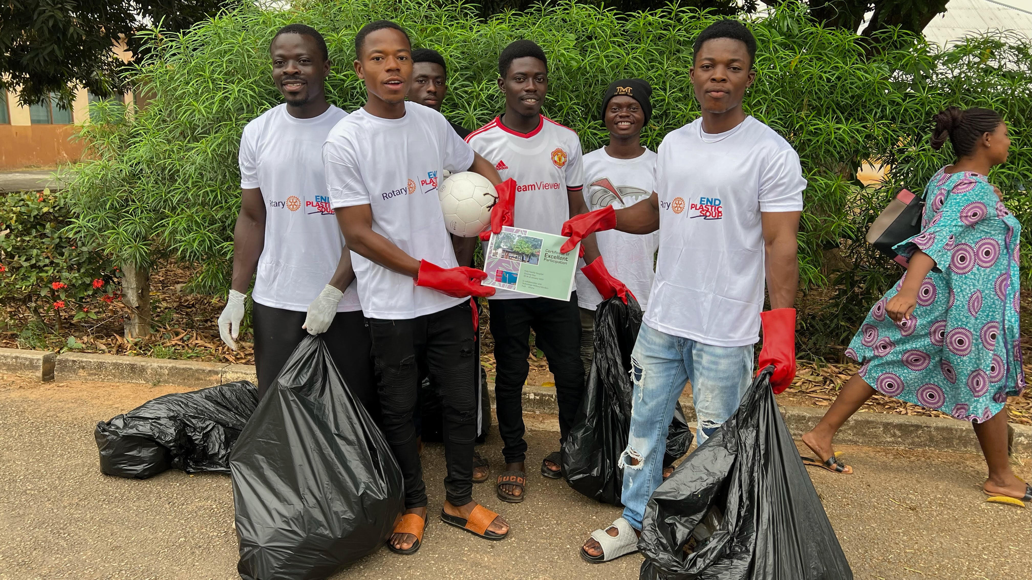 a group of individuals in white shirts holding trash bags