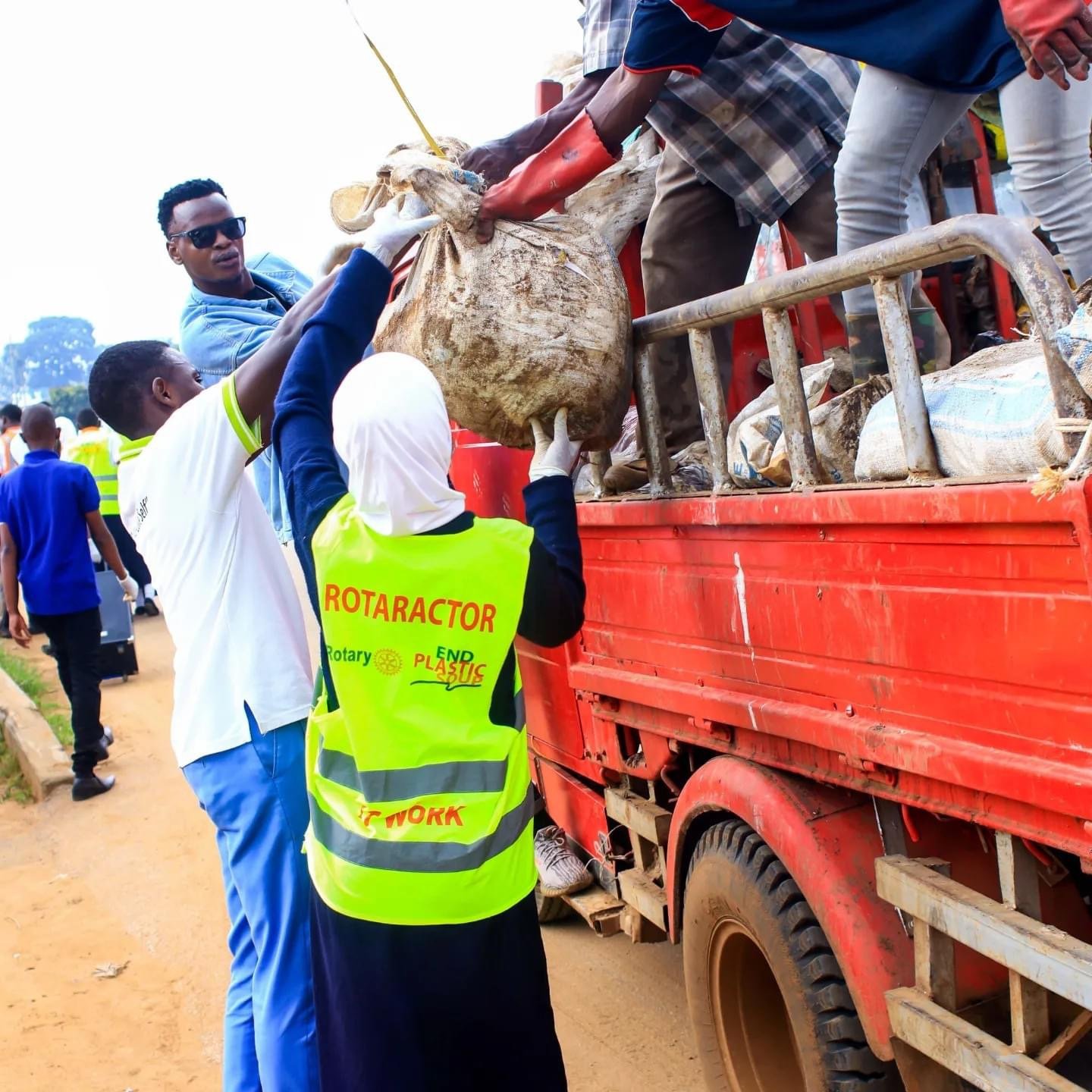 a group of people loading plastic rubbish onto a truck