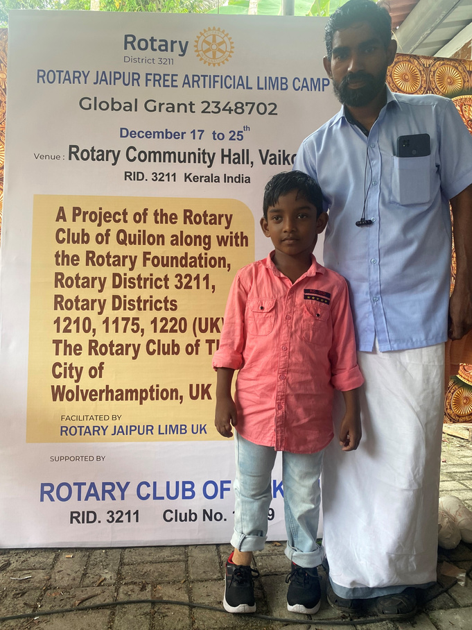 A father and son standing in front of a Rotary pull-up banner.