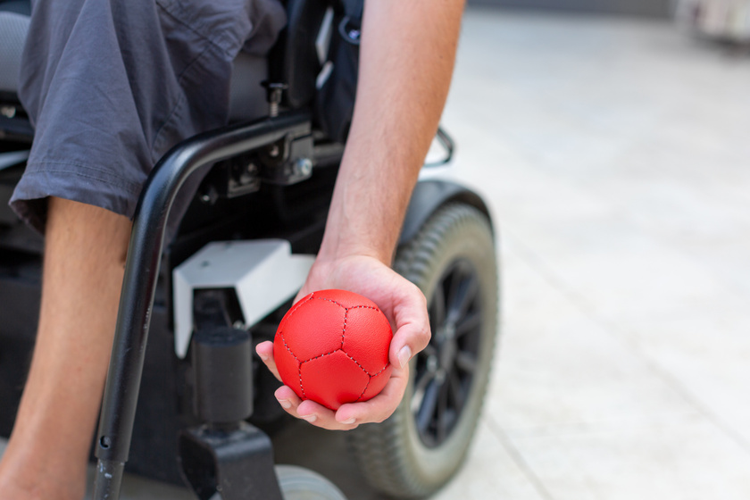A person in a wheelchair holding a red ball.