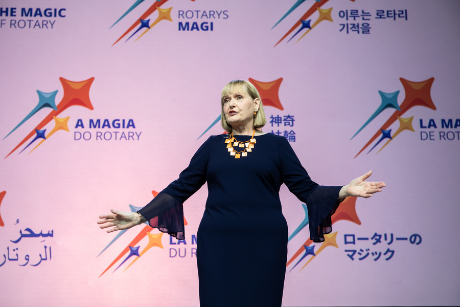 Stephanie Urchick standing in front of a stage with their arms outstretched.