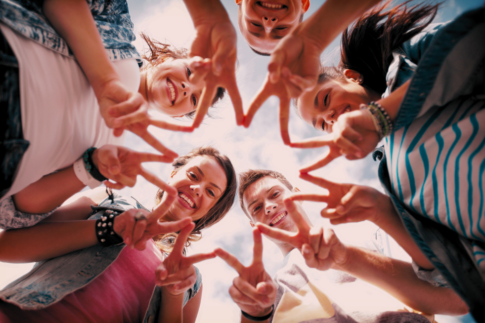 A group of young people making a star with their hands.
