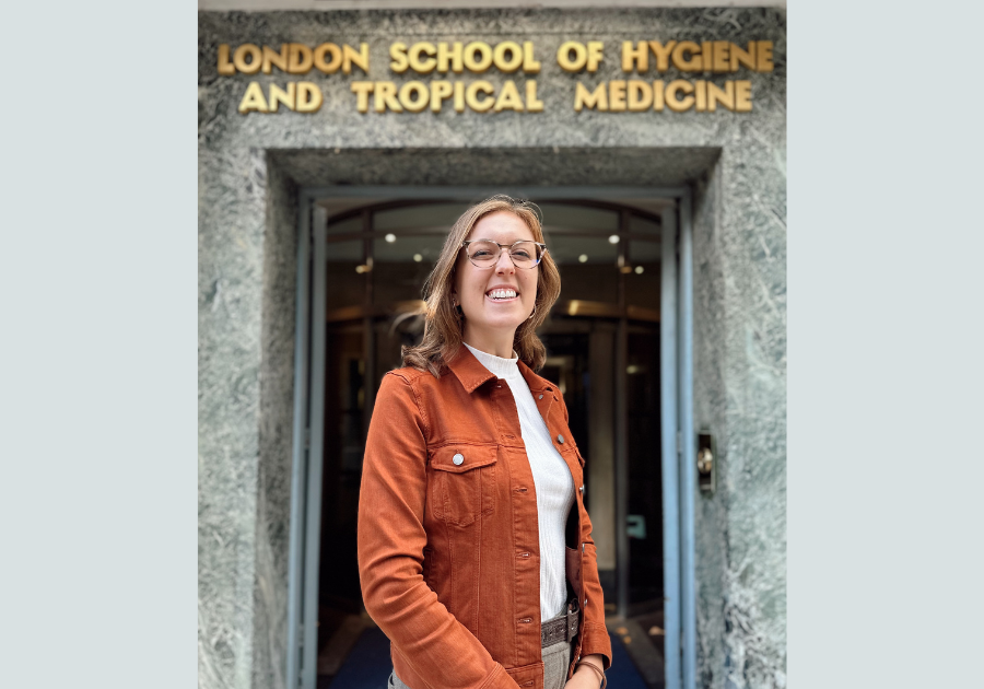 Ashlyn Anderson in an orange jacket standing in front of a door