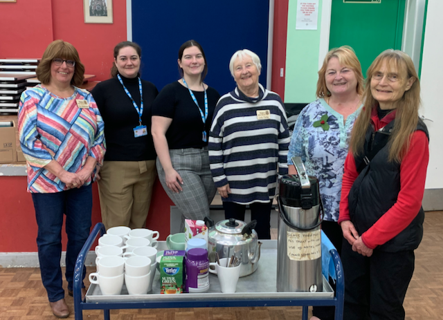 a group of people standing next to a cart full of coffee cups