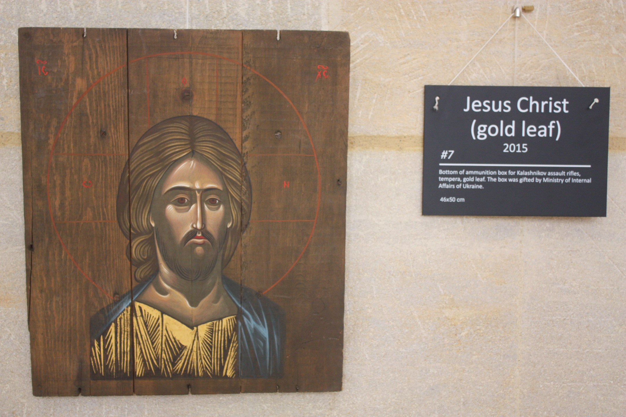 A painting of the Jesus is painted decoratively on a scorched wooden board.