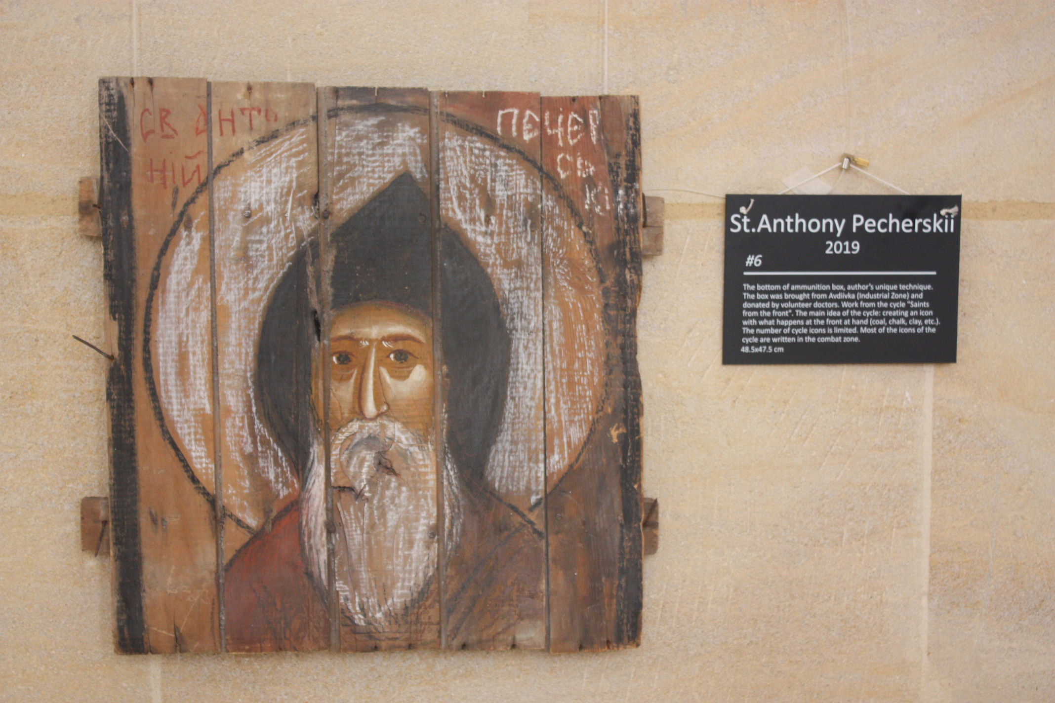 A painting of a Saint is painted decoratively on a scorched wooden board.