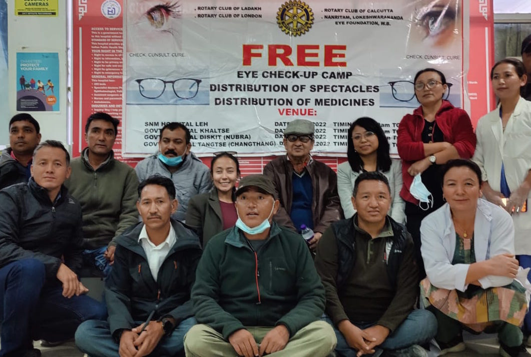 a group of people posing for a photo in front of a banner advertising free eye check-ups