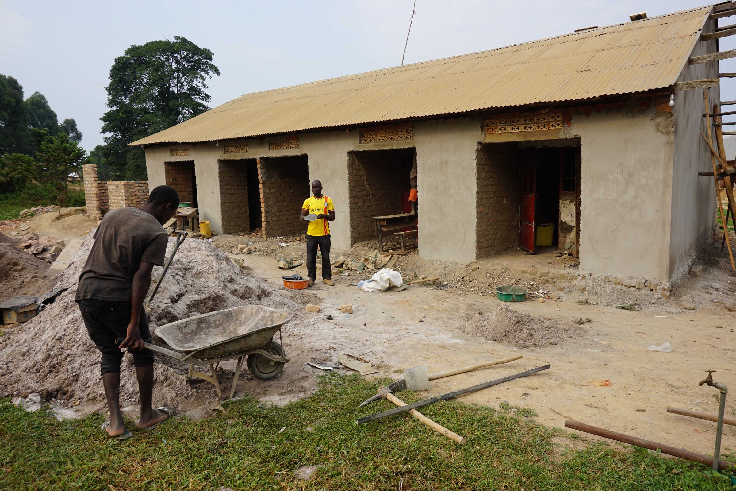 Two people building a house in a rural area of Uganda.