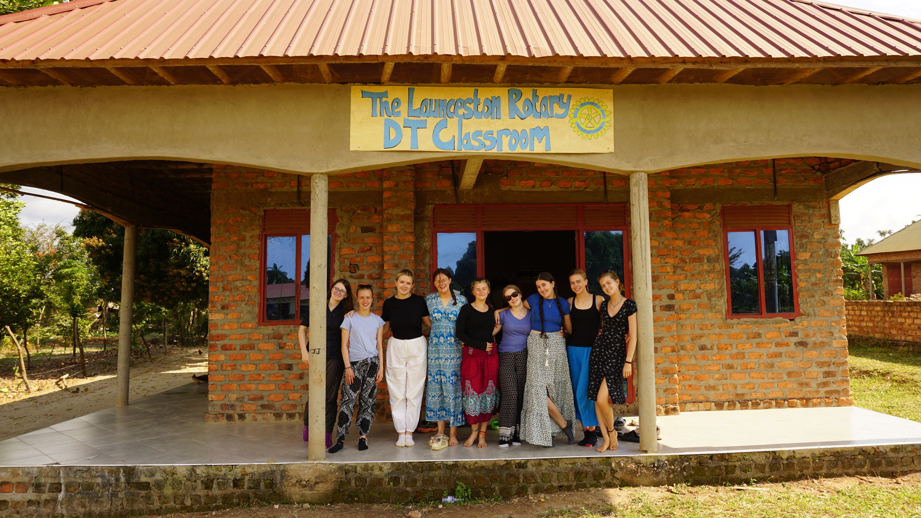 A group of students standing in front of a building in Uganda.