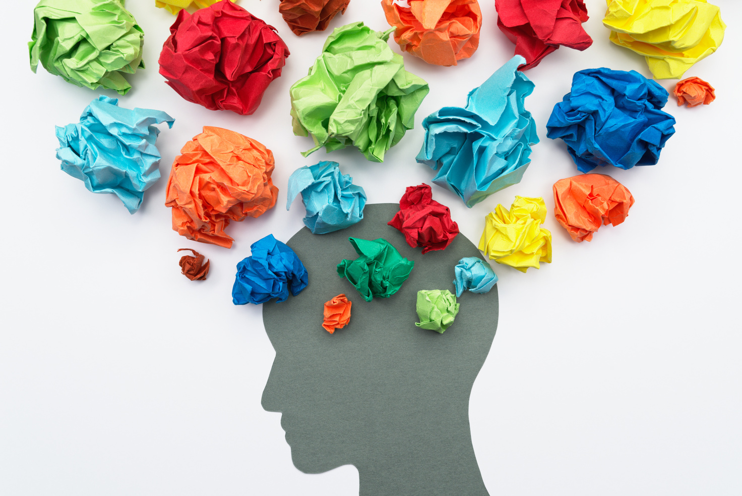 A mental health stock illustration of a person's head filled with colorful crumpled paper.