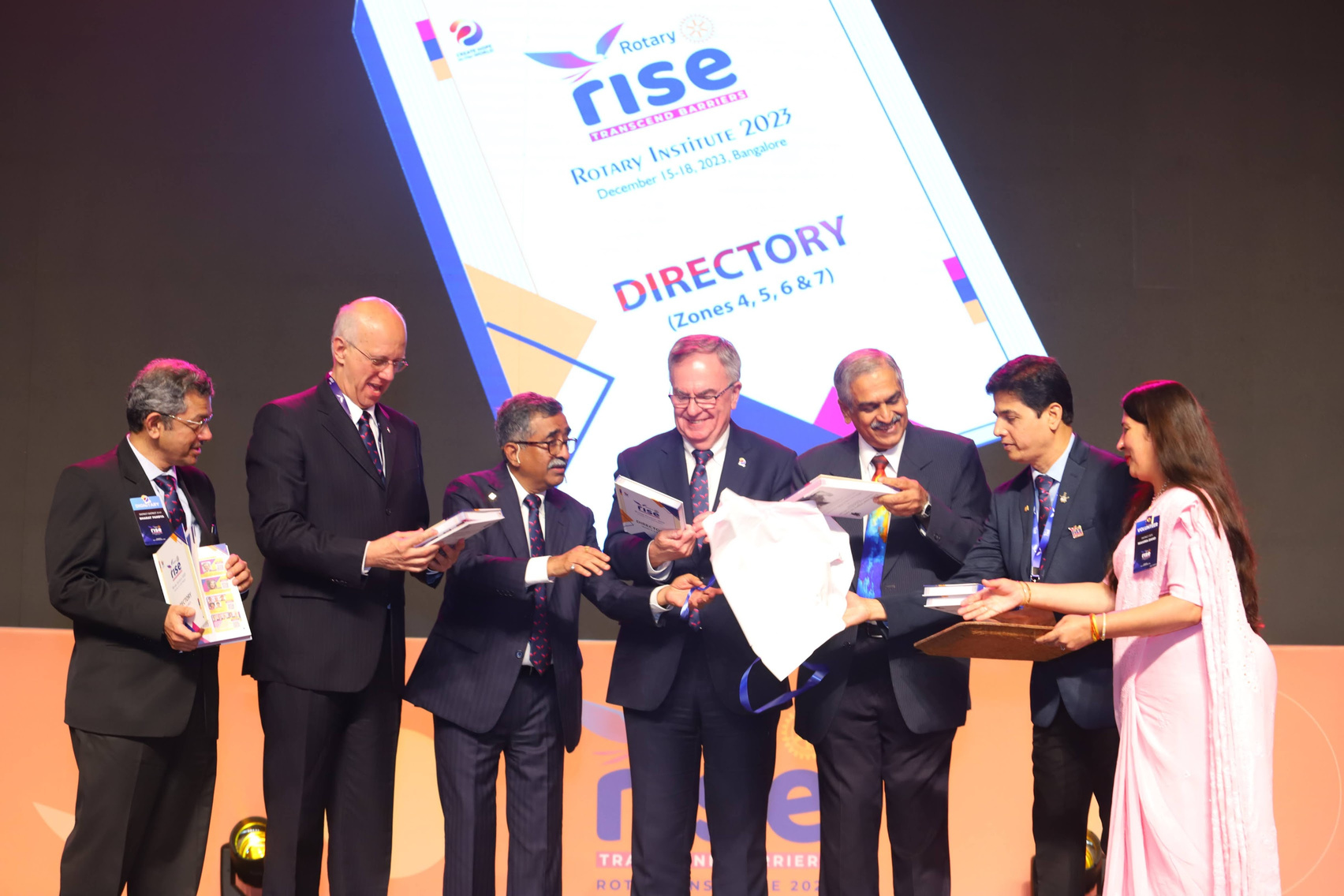 RI President Fordon McIanlly on stage with Rotarians from India holding a book