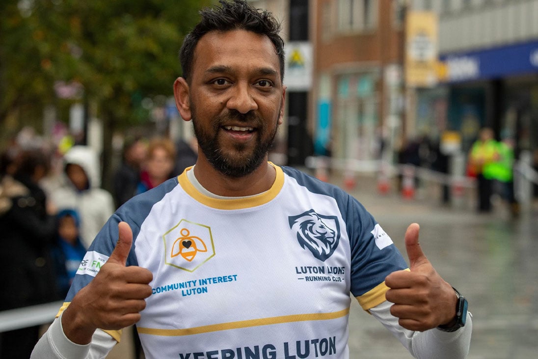 Mostaque Koyes giving the thumbs up in front of a crowd during a marathon.