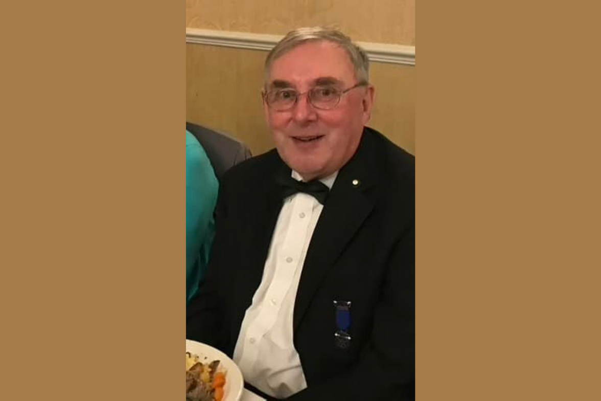 Robin Varley in a tuxedo sitting at a table with a plate of food.