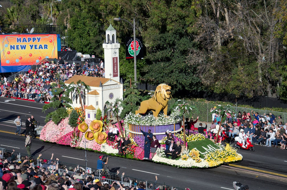 A float at the Rose Parade with a lion and flowers on top of it.