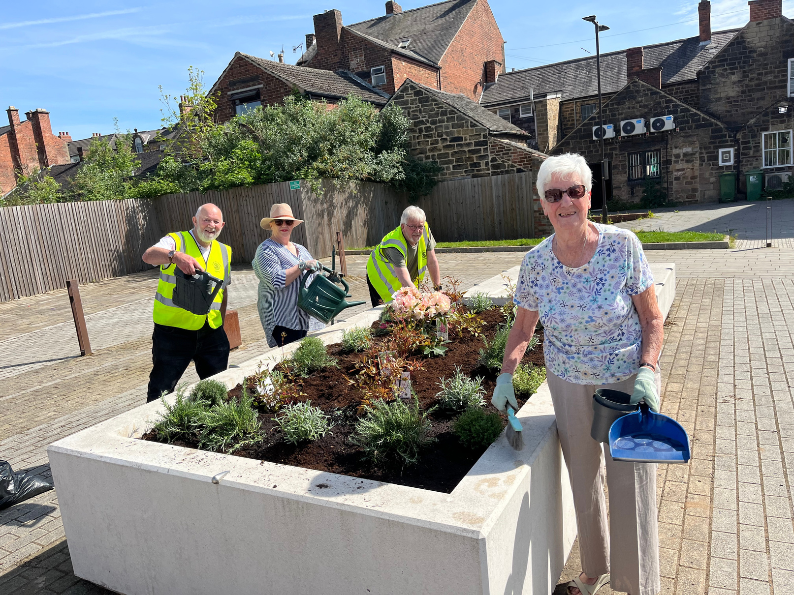 a group of people are planting flowers in a planter