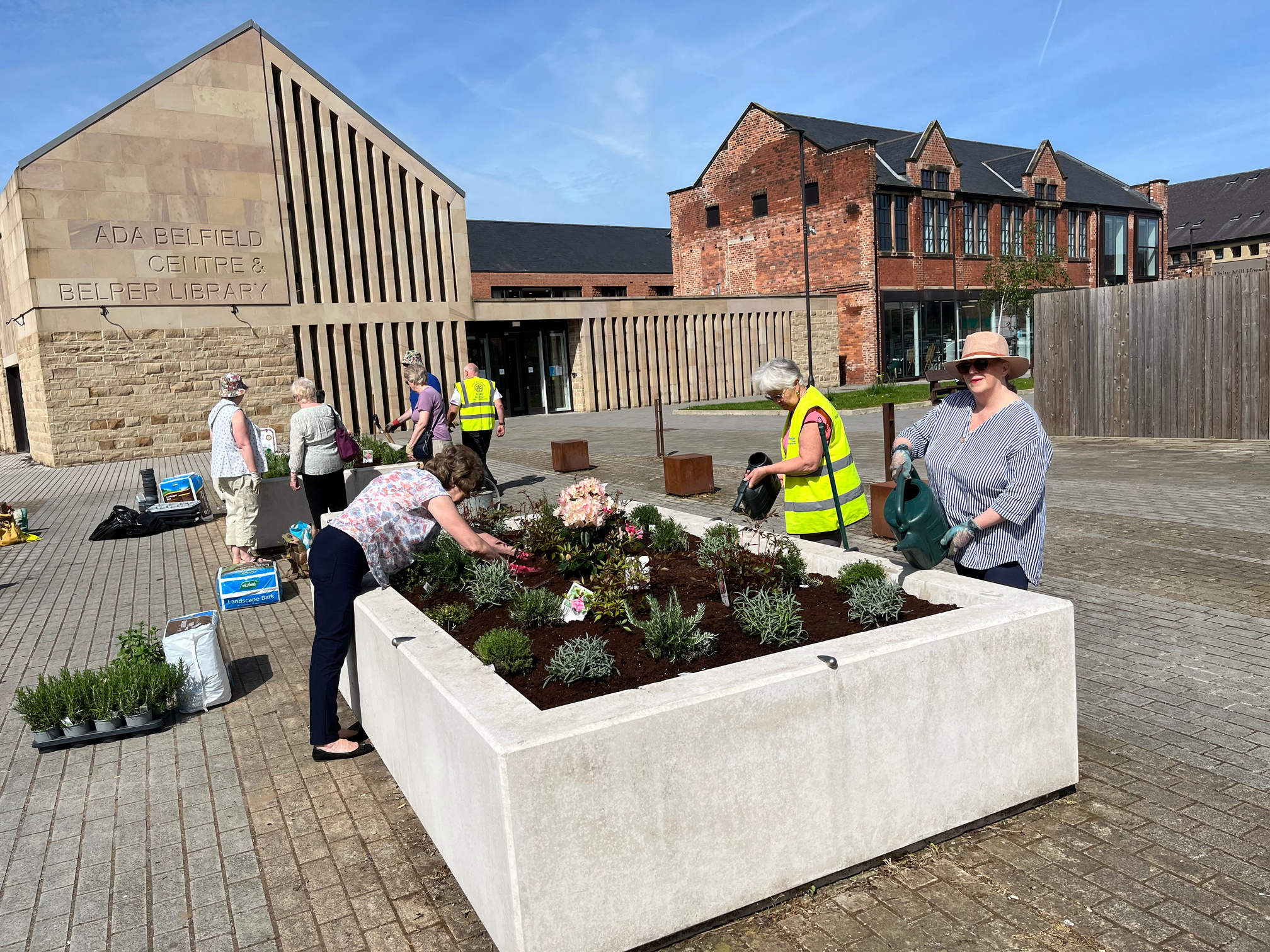 a group of people working on a planter in front of a building