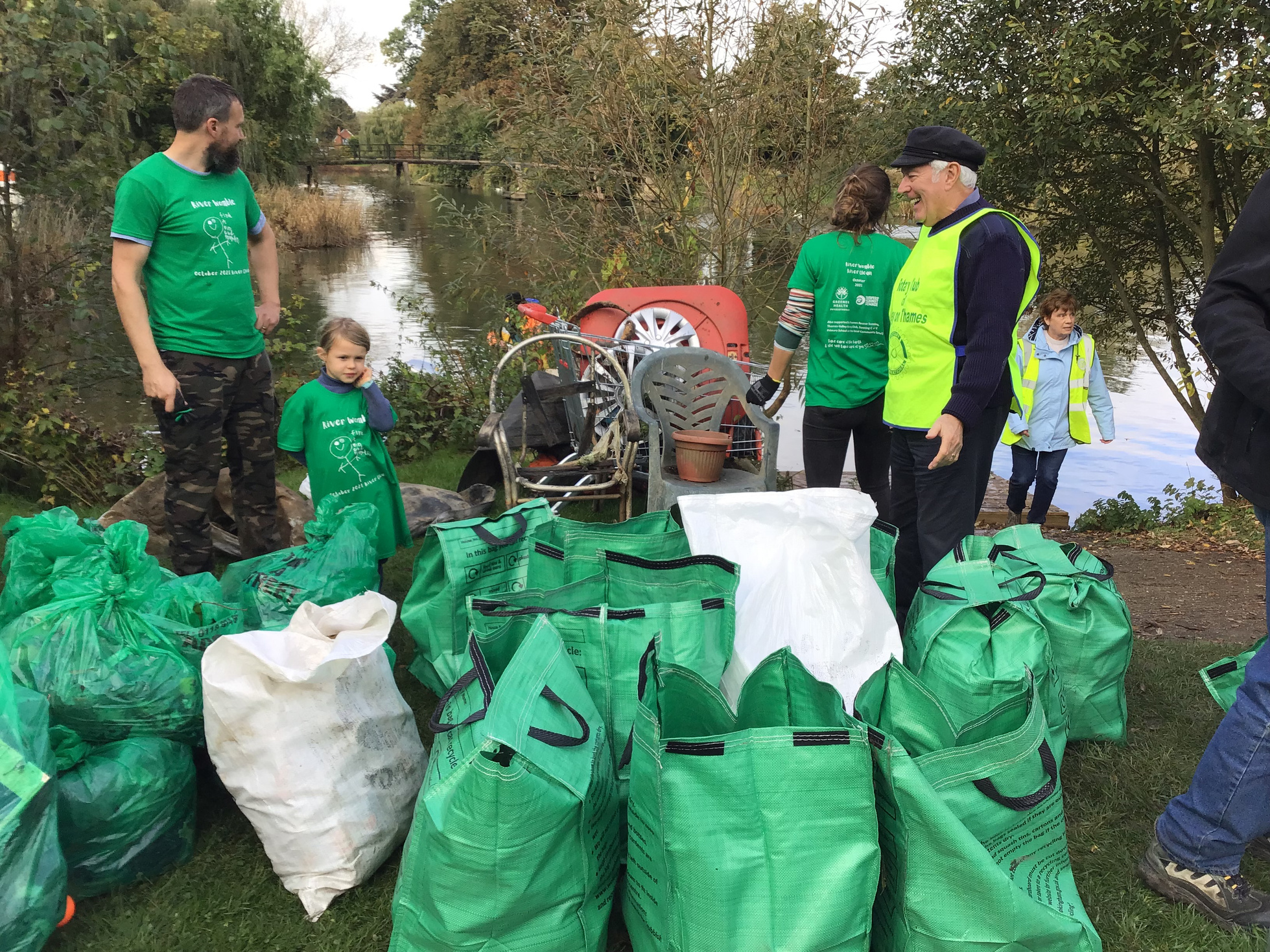 a group of volunteers standing with bags of rubbish they have collected from a river