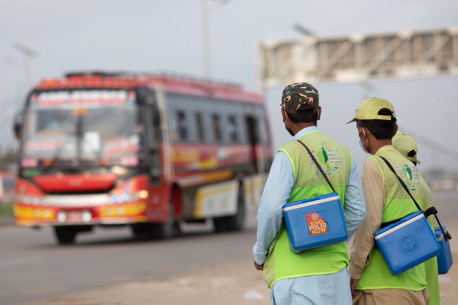 Three male polio workers waiting for a bus.