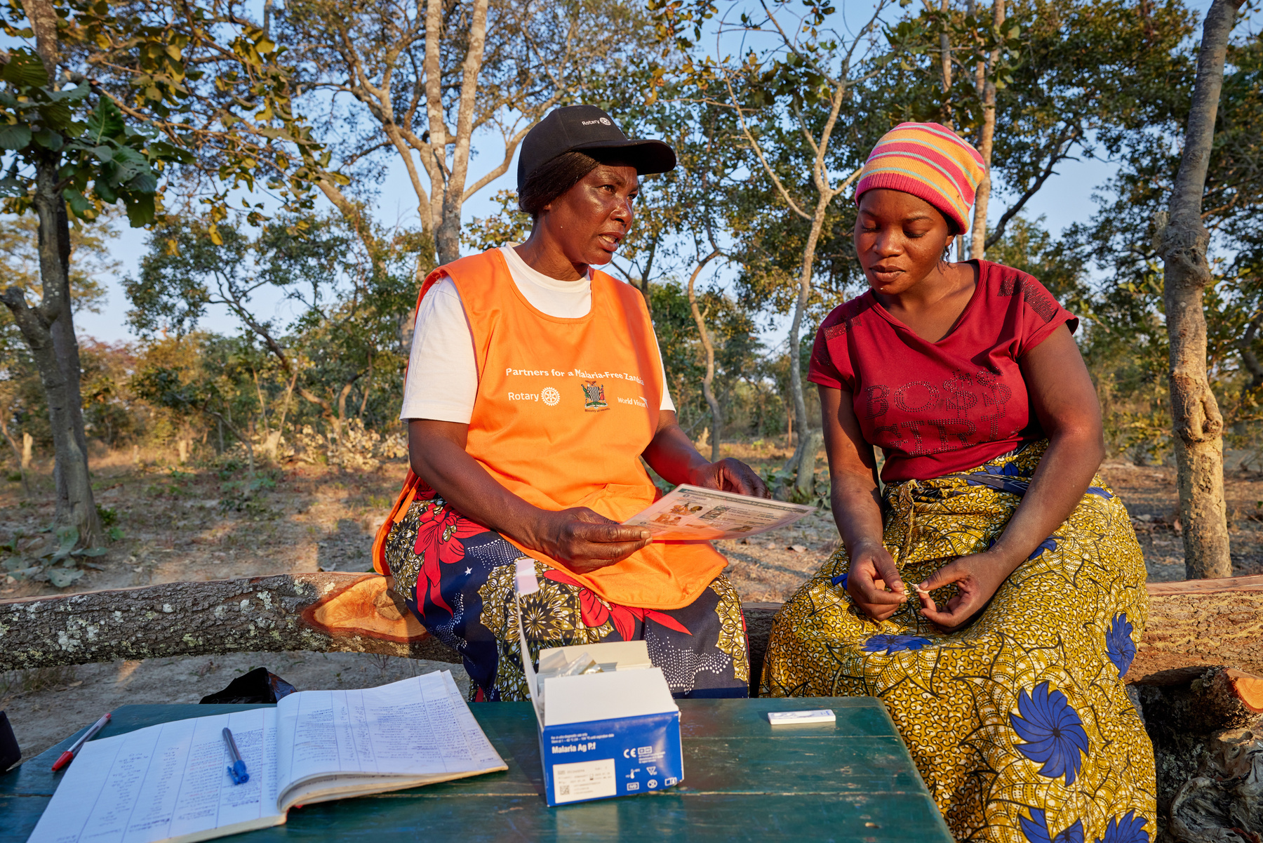 Two volunteers in Zambia talking whilst sat on a tree trunk