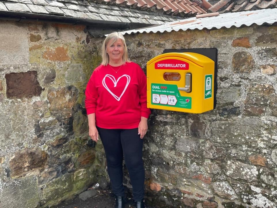 a person in a red shirt standing next to a defibrillator box