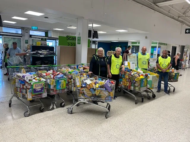 a group of people standing in a supermarket with trolleys full of food