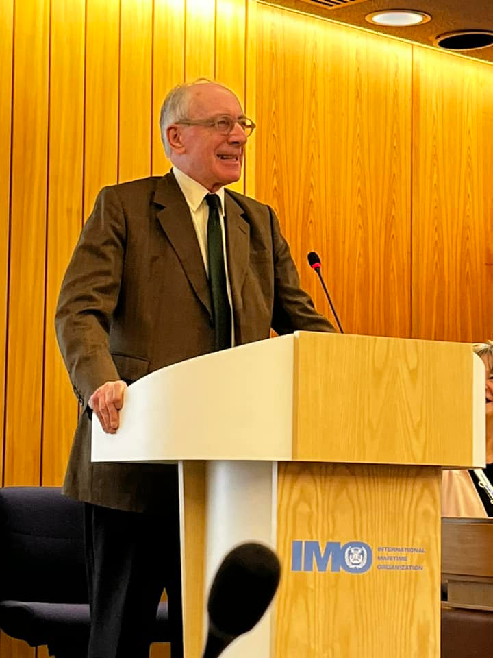 Sir Malcolm Rifkind standing at a podium in front of a wood-panelled wall at the Presidential Peace Conference.