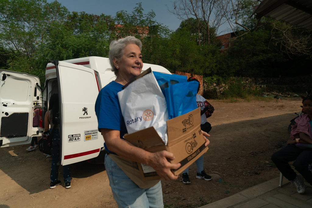 A person carrying a box of food in front of a van