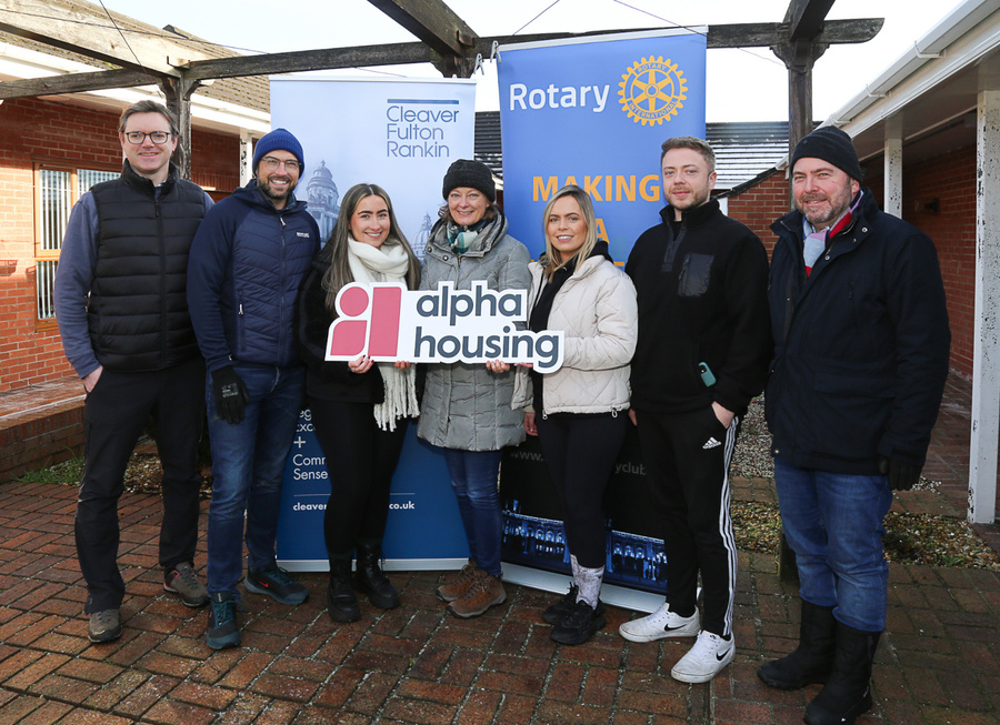 a group of people standing in front of a sign that says alpha housing