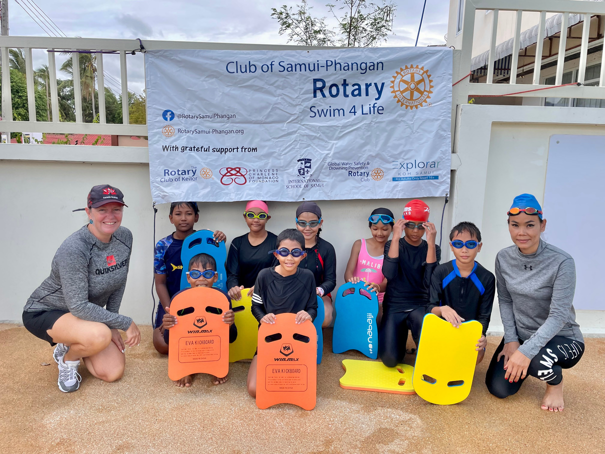 a group of people posing for a photo in front of a sign that says "rotary swim team"