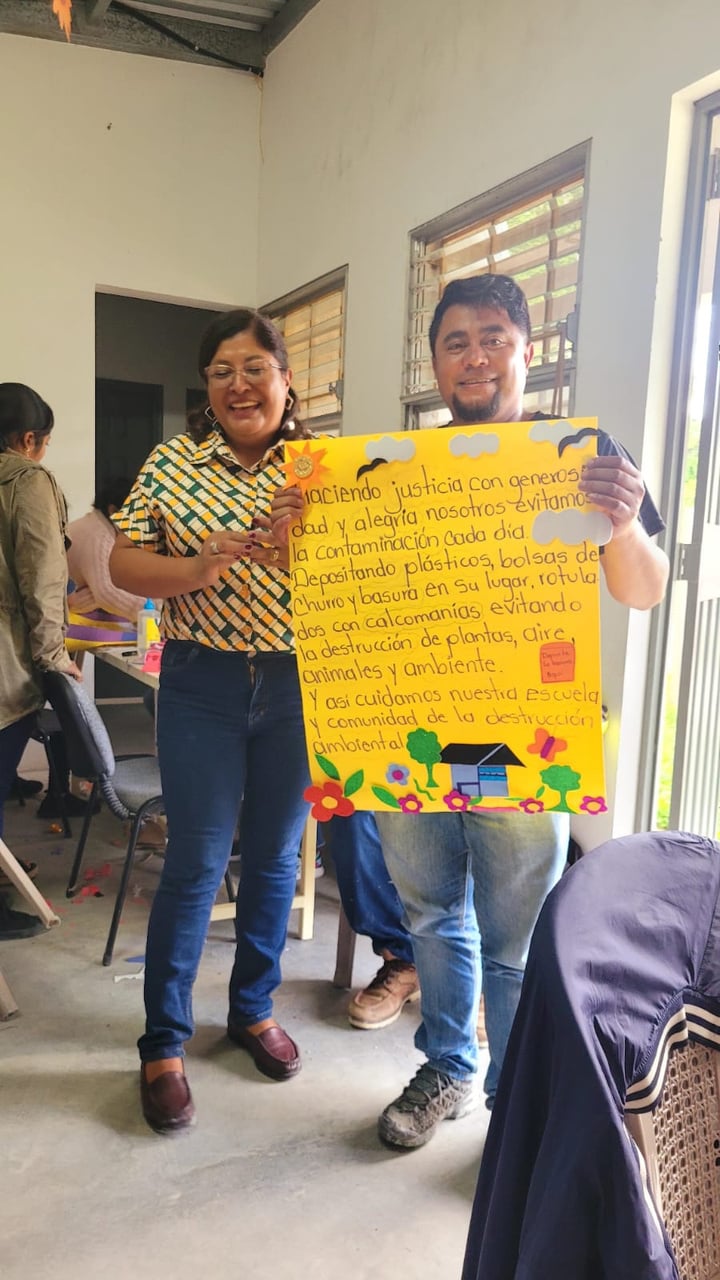 Two people from Honduras holding up a sign with Spanish writing on it.