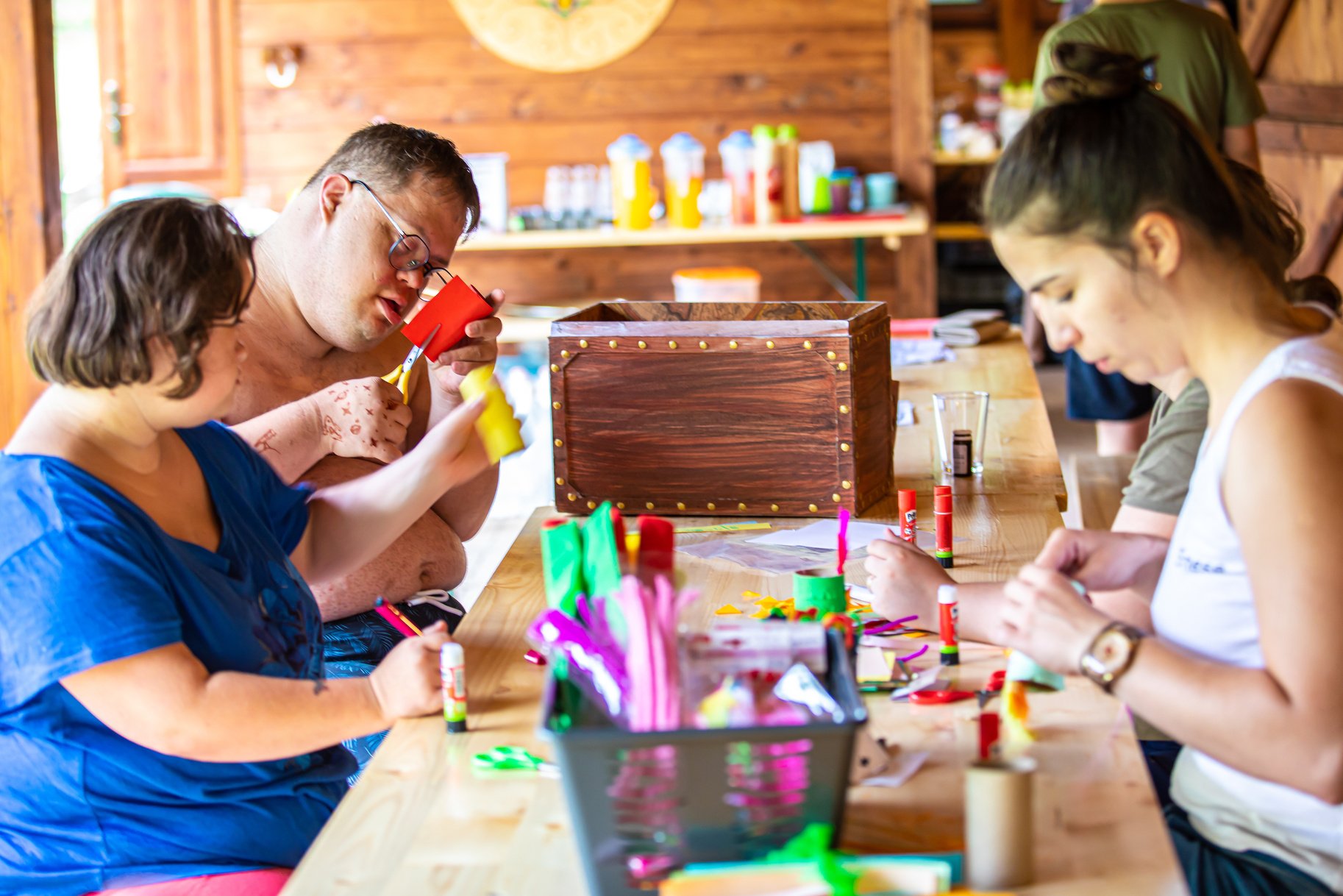 a group of people with Down Syndrome sitting around a table making crafts