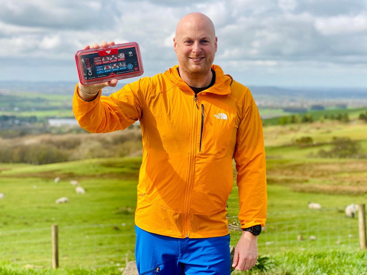 a person in an orange jacket holding up an electronic device