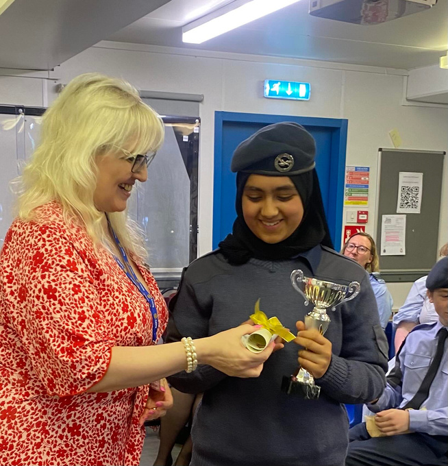 An adult hands out an award to a teenage girl