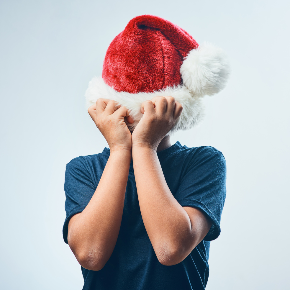 a person covering their face with a santa hat